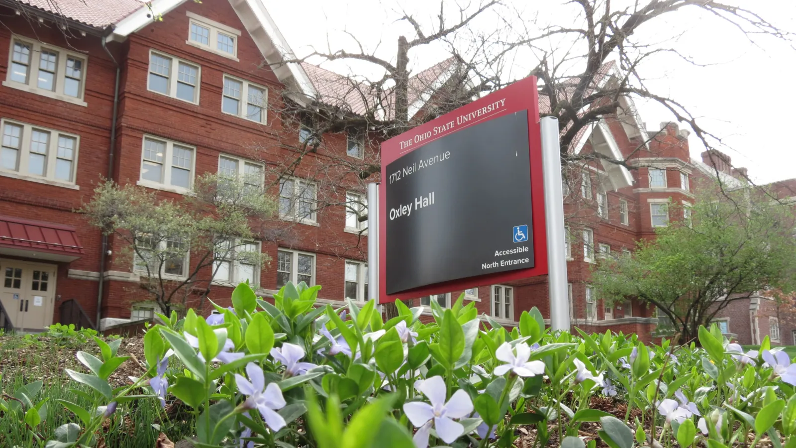 Oxley Hall sign, with building in background and spring flowers in foreground