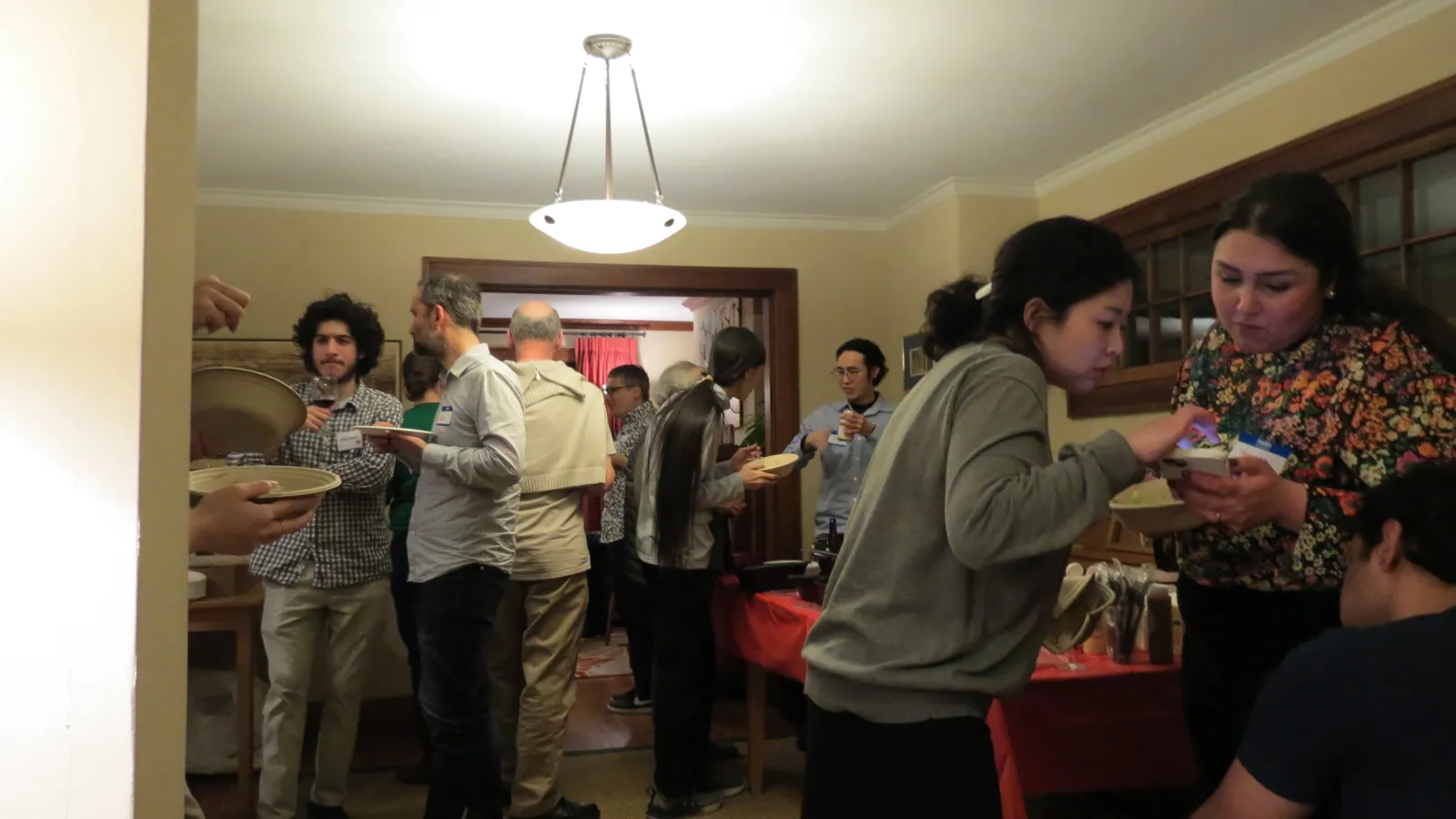 group of individuals standing around a room, talking and eating