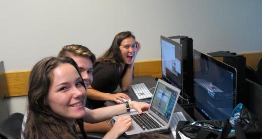 Students posing for a pictures in front of computers