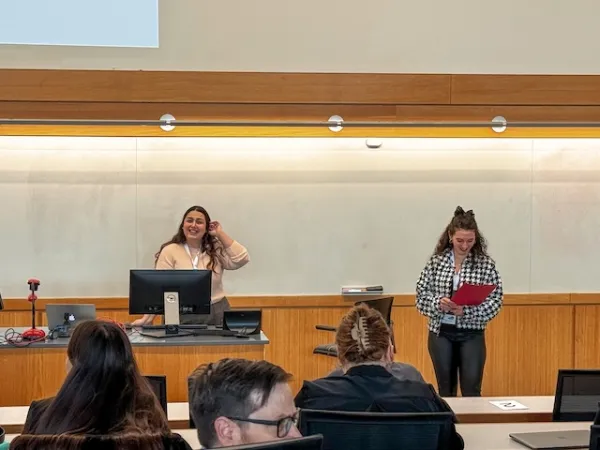 two students presenting at the conference, standing in front of the group