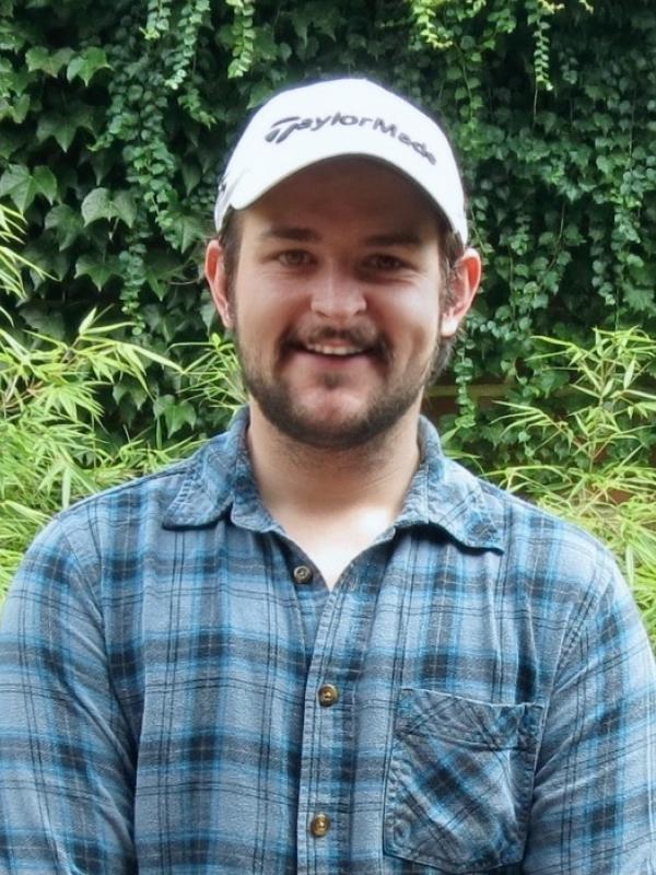 headshot of kyler wearing blue plaid shirt and white hat; smiling
