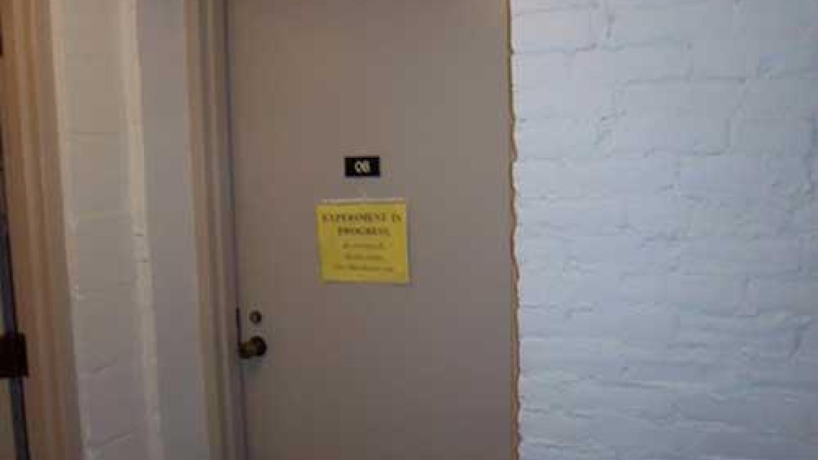 Sound booth door closed with a sign "Experiment in Progress" (slide 2 of 2)