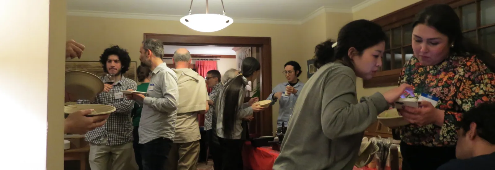 group of individuals standing around a room, talking and eating