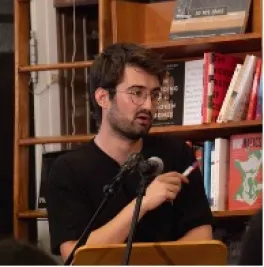 Adam Aleksic speaking into a microphone