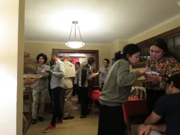 various faculty and students standing in a room visiting in groups
