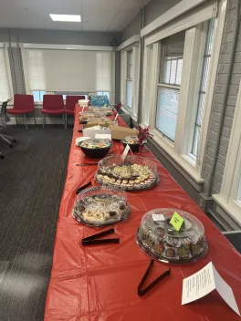view of long table with a red tablecloth, with trays of food on it